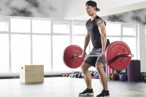 Азиатский мужчина поднимает штангу в спортзале — стоковое фото