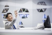 Jeune homme d'affaires chinois volant avion en papier au bureau — Photo de stock
