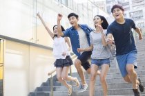 Китайские друзья бегут по ступенькам на улице — стоковое фото