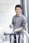Chinese businessman drinking coffee in office — Stock Photo