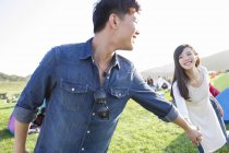 Chinese couple holding hands on music festival lawn — Stock Photo