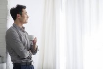 Asiatischer Geschäftsmann trinkt Kaffee im Büro — Stockfoto