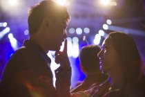 Chinese woman putting finger on male lips at music festival — Stock Photo
