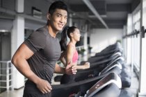 Chinese couple exercising on treadmills in gym — Stock Photo