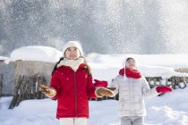 Chinese girls catching falling snow outdoors — Stock Photo
