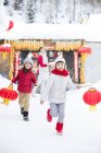 Crianças correndo com lanternas chinesas com a mãe no fundo — Fotografia de Stock
