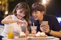 Jovem casal chinês tirando foto de sobremesa no café — Fotografia de Stock