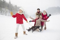 Chinese family of three generations posing with sled on snow — Stock Photo