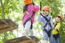 Chinese children climbing on trees in adventure park — Stock Photo