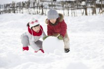 Chinesische Kinder rollen Schneeball im Freien — Stockfoto
