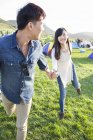 Chinese couple running and holding hands on grass — Stock Photo