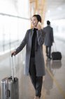 Asian woman talking on phone at airport — Stock Photo