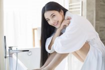 Chinesische Frau sitzt im Badezimmer im Bademantel — Stockfoto