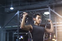 Hombre chino entrenando con pesas en gimnasio crossfit - foto de stock