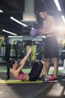 Femme chinoise travaillant avec entraîneur et balle à la salle de gym — Photo de stock