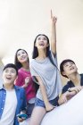 Chinese friends pointing and looking at view — Stock Photo