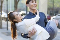 Homem chinês carregando namorada nos braços na rua — Fotografia de Stock