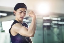 Asian man in sports clothing flexing muscles — Stock Photo