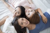Amigos femininos deitados na cama — Fotografia de Stock