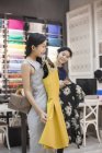 Chinese clothing store owner helping customer choosing dresses — Stock Photo