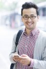 Asiatico uomo utilizzando smartphone su strada — Foto stock