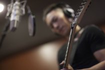 Homem chinês tocando guitarra no estúdio de gravação — Fotografia de Stock