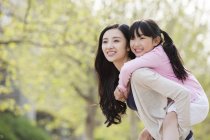 Азіатські мати їзда дочка piggyback в парку — стокове фото