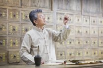 Mature médecin chinois examinant les herbes médicinales — Photo de stock