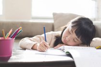 Tired chinese girl doing homework — Stock Photo