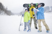 Chinese family holding snowboards on slope — Stock Photo