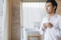 Chinese man buttoning shirt — Stock Photo