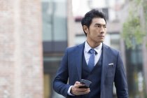 Hombre asiático sosteniendo teléfono inteligente en la calle urbana - foto de stock
