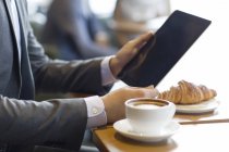 Vista ravvicinata delle mani maschili che tengono il tablet digitale nel caffè — Foto stock