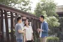 Chinese friends with coffee talking in city — Stock Photo