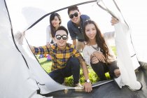 Chinese friends entering tent at camping — Stock Photo