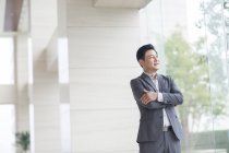Asian businessman standing with arms folded — Stock Photo