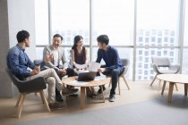 Equipo de empresarios chinos discuten trabajo en reunión - foto de stock