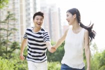 Jeune couple chinois tenant la main tout en marchant dans le parc — Photo de stock