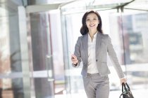 Mujer de negocios asiática caminando con smartphone - foto de stock