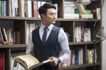 Asiatischer Geschäftsmann liest Buch in Studie — Stockfoto