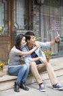 Chinese couple taking selfie with smartphone on street — Stock Photo
