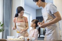 Genitori cinesi con figlia che cucinano insieme in cucina — Foto stock