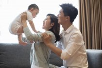Chinese parents lifting baby boy at home — Stock Photo