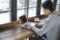 Китаец использует ноутбук в кафе — стоковое фото