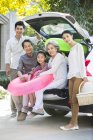 Chinese family sitting in open car trunk with inflatable ring — Stock Photo