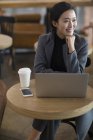 Азіатський жінка очікування в аеропорту з кавою і ноутбук — стокове фото