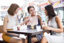Female friends trying on clothes at sidewalk cafe — Stock Photo