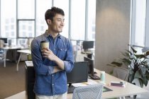 Jovem chinês tomando café pausa no escritório — Fotografia de Stock