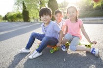 Китайские дети сидят на скейтборде — стоковое фото