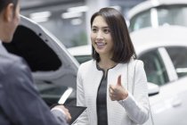 Chinese auto mechanic talking with car owner — Stock Photo